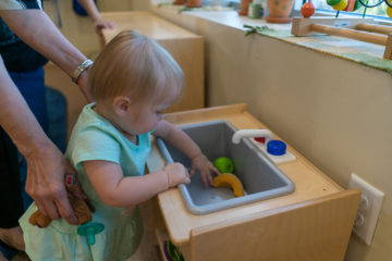 toddler learning to wash fruits at our daycare center
